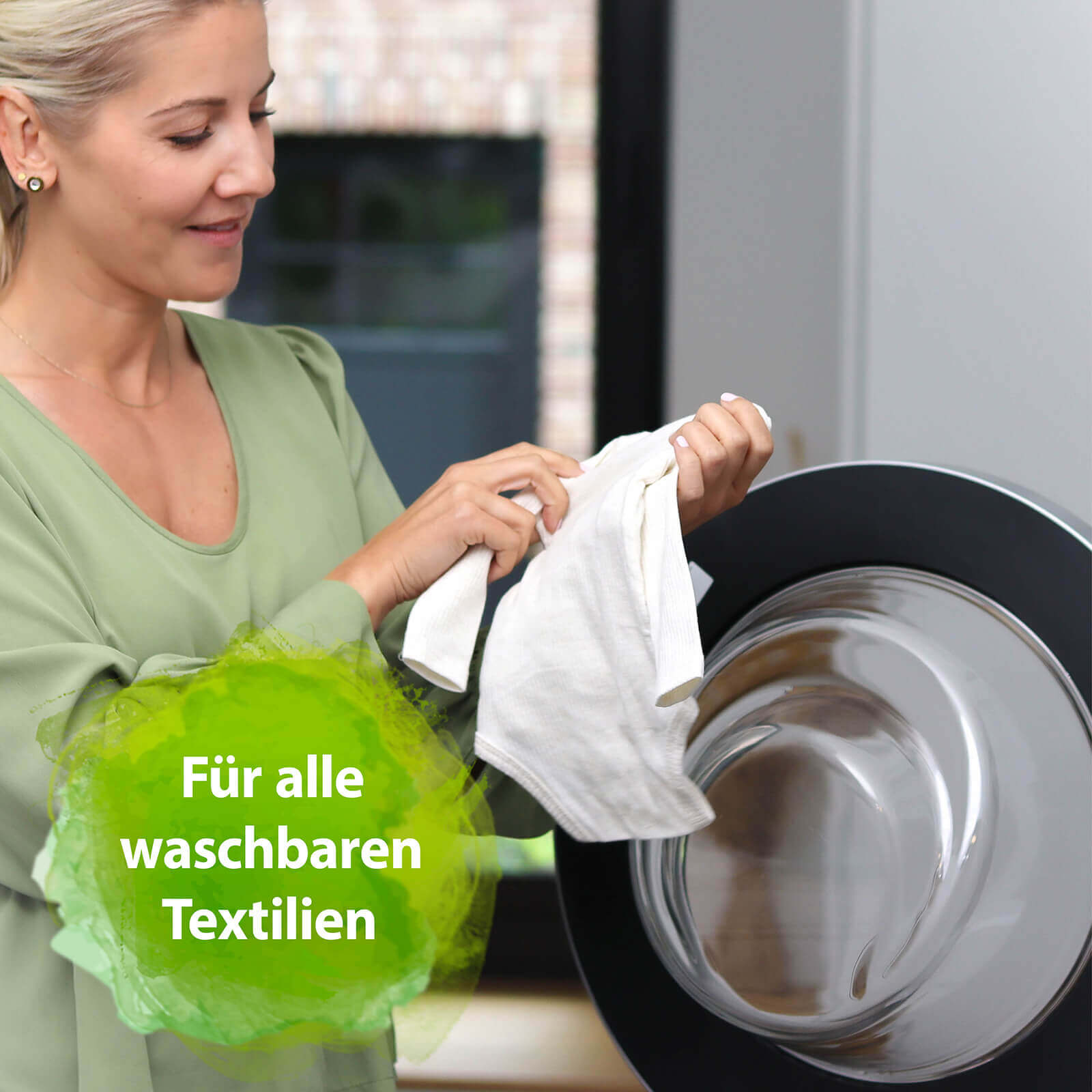 Frau hält Strampler vor Waschmaschine in der Hand - Für alle waschbaren Textilien