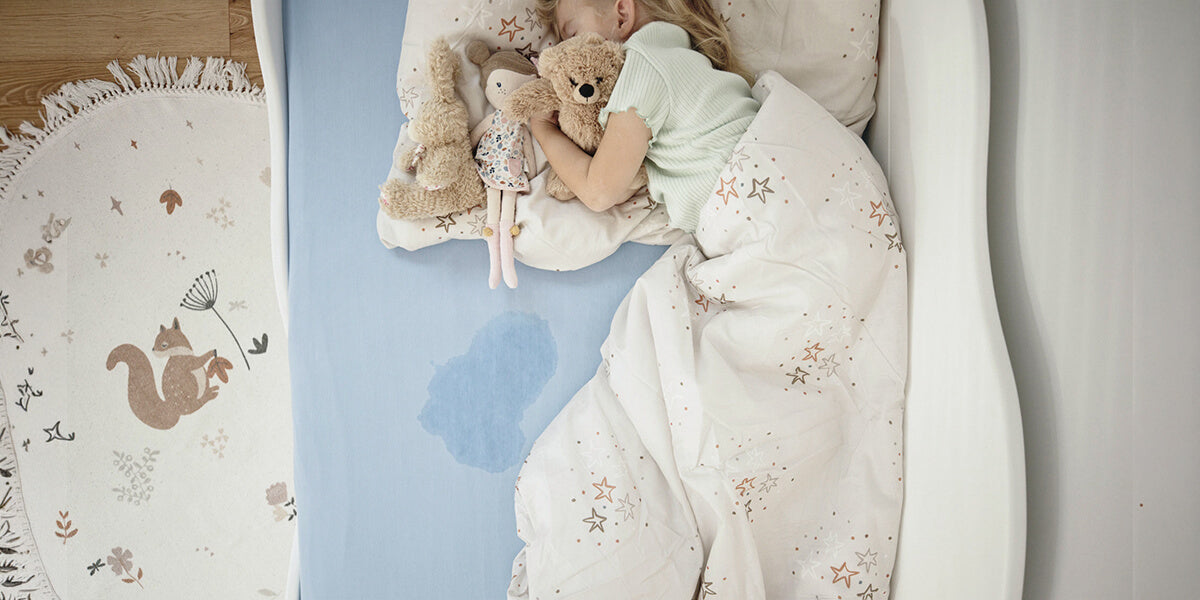 Kind im Bett mit Urinfleck auf der Matratze